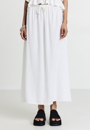 Weiße Maxikleid mit einem Kordelzug in der Taille und einem fließenden Design. Kombiniert mit schwarzen Plateausandalen. Glatte Stofftextur.