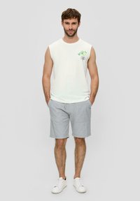 Sleeveless white cotton shirt with green citrus graphic, paired with light gray shorts featuring two front pockets and a drawstring waist.