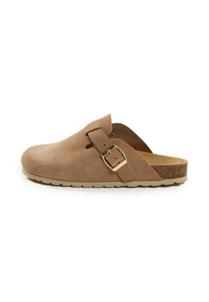 Zueco de ante color tostado tipo slip-on con puntera cerrada, correa ajustable con hebilla, plantilla de corcho y suela de goma texturizada, mostrado de perfil.