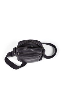 Borsa a tracolla in pelle nera con tracolla in cotone. Presenta diversi scomparti con zip e una superficie texturizzata con un dettaglio di branding discreto.