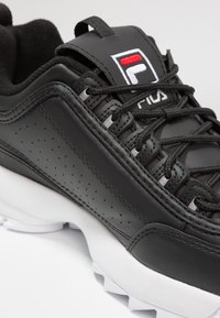 Schwarzer Leder-Laufschuh mit perforierten Akzenten, Schnürverschluss und einer weißen Gummisohle. Fila-Logo auf der Zunge angebracht.