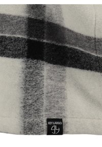 Grau-weißes Karomuster-Fleecegewebe mit weicher Textur, versehen mit einem schwarzen "KEY LARGO"-Label, das an der Kante angenäht ist.