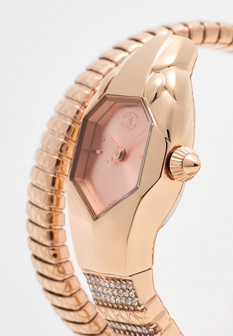 Reloj hexagonal de oro rosa con esfera rosa, pulsera de metal texturizado y acentos de cristal en la correa, con una corona prominente.