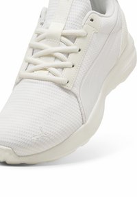 Scarpa sportiva bianca con parte superiore in mesh testurizzata, lacci piatti e suola ammortizzata. Presenta un logo discreto sul lato e accenti lisci.