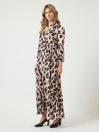 Žena v dlhom rukáve, s košeľovým maxi šatami s béžovým, čiernym, ružovým a olivovým zvieracím vzorom, v kombinácii s čiernymi lodičkami na vysokom podpätku.