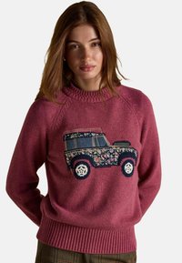 Noor naine heledate pruunide juustega kannab roosa kudumit, millel on lillelise mustriga maastikusõiduki disain.