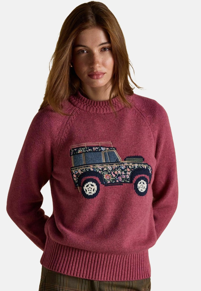 Noor naine heledate pruunide juustega kannab roosa kudumit, millel on lillelise mustriga maastikusõiduki disain.