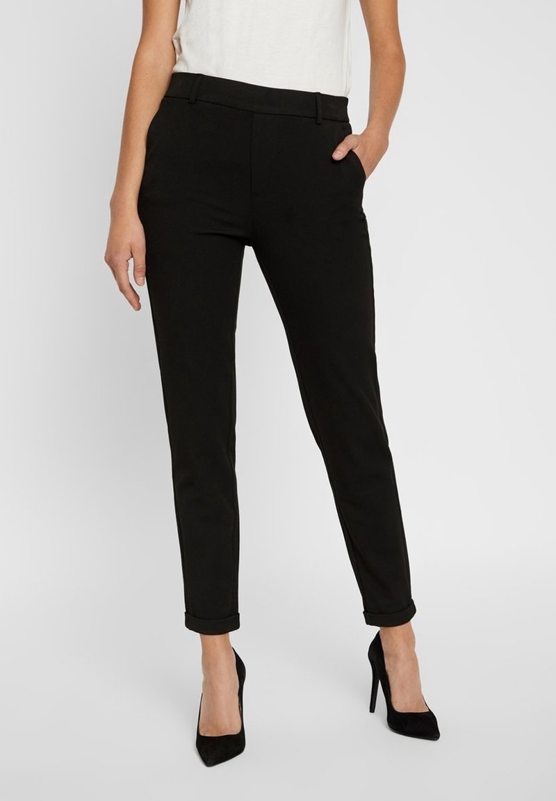 Black fitted trousers with a slim design, featuring side pockets and cuffed hems, made from a smooth material. Paired with black high heels.