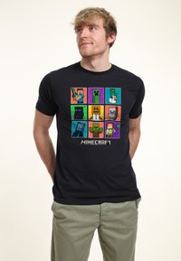 Black short-sleeve t-shirt featuring a grid of Minecraft character graphics in various colors. "Minecraft" logo printed at the bottom.