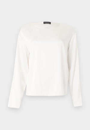 T-shirt blanc à manches longues avec col rond, coupe décontractée, présenté sur un fond gris clair uni.