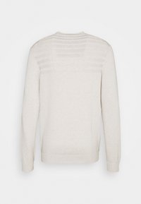 Vaaleanbeige svetari, jossa pitkät hihat, resorit hihansuissa ja helmassa, yläselässä kohokuvioitu raidallinen kuvio. Sileä neulospinta.