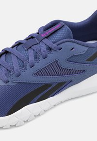 Violet sportiniai batai su tinklelio audiniu, guminiais padais, tekstūruotais intarpais ir juodais akcentais. Reebok logotipas rožinės spalvos šalia raiščių.