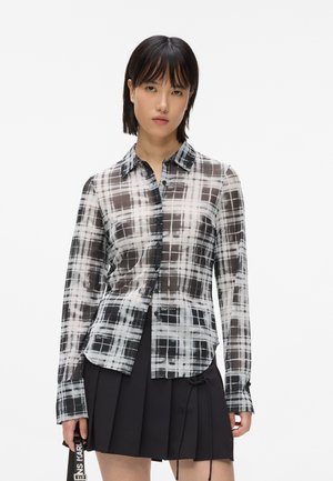 Doorzichtig, lang mouw plaid overhemd in zwart, wit en grijs. Voorzien van een knoopsluiting aan de voorkant, klassieke kraag en gebogen zoom.