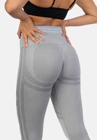 Szare legginsy o wysokim stanie z żeberkowym pasem, charakteryzujące się bezszwowym designem oraz delikatnym szarym pasem ranem wzdłuż nogawek i detalami konturowymi.