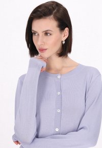 Ljus lavendelfärgad cardigan, mjukt stickad tyg, rund halsringning, sex knappar framtill, långa ärmar, med ribbade manschetter och nederkant.