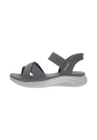 Sándal gris con tiras cruzadas y detalles elásticos. Cuenta con una plantilla acolchada y una suela curvada de goma blanca. Diseño ligero.