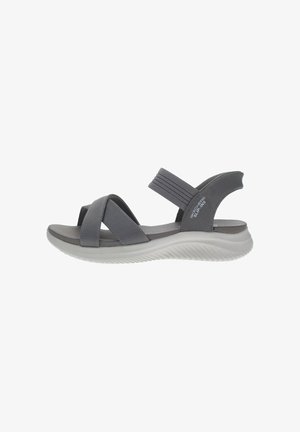 Sandalo grigio con cinturini incrociati e accenti elastici. Presenta una soletta imbottita e una suola in gomma bianca curvata. Design leggero.