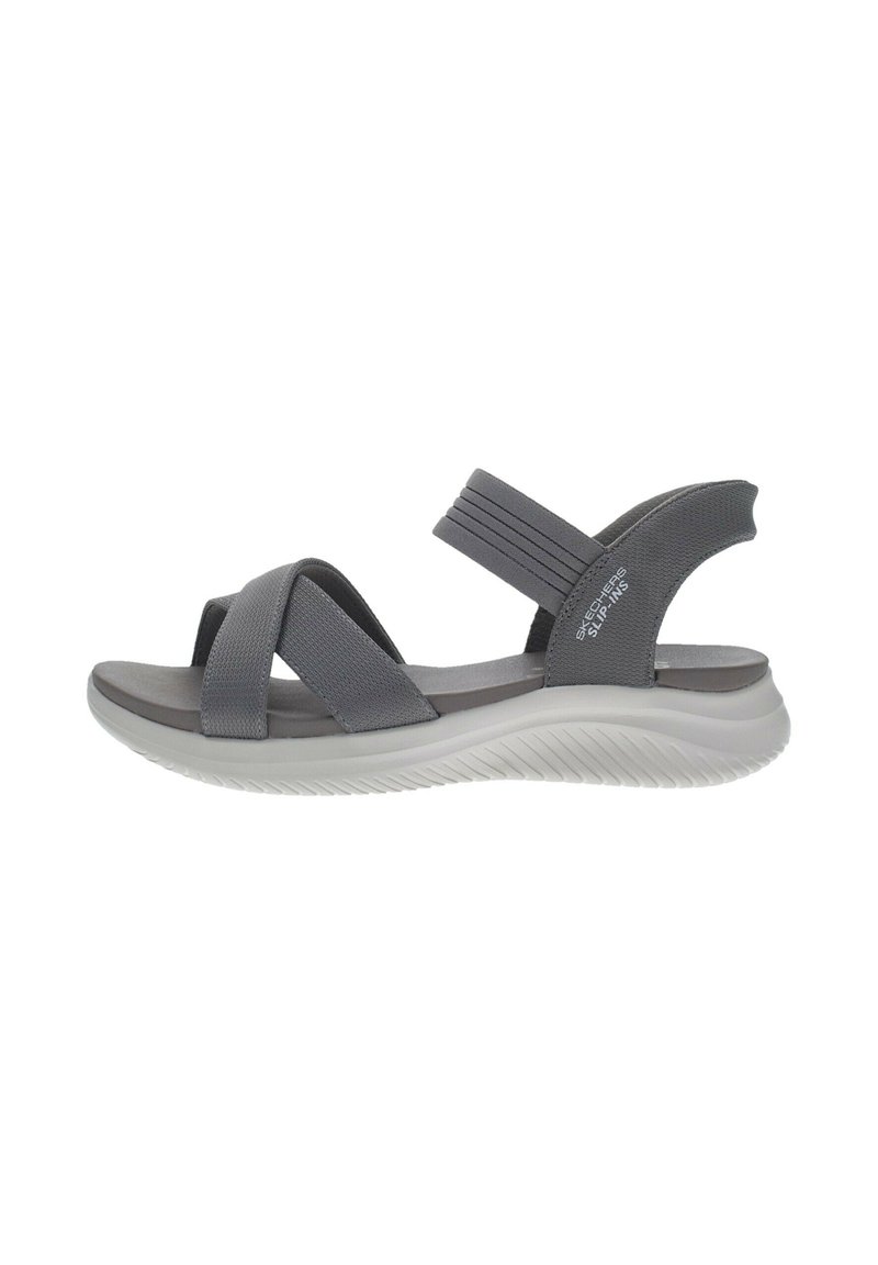 Sándal gris con tiras cruzadas y detalles elásticos. Cuenta con una plantilla acolchada y una suela curvada de goma blanca. Diseño ligero.