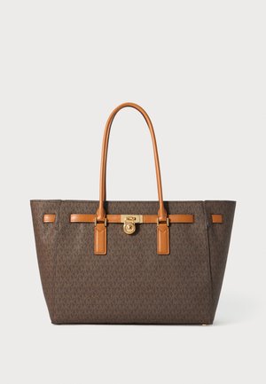 Borsa a tote monogrammata marrone con dettagli in pelle caramello, accessori in oro, due manici lunghi e un design strutturato.