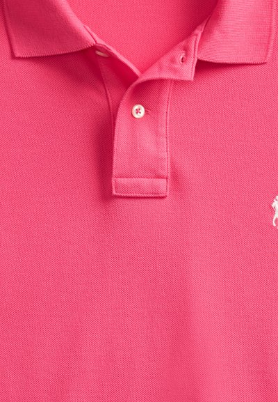 Polo rosa con colletto, due bottoni e un piccolo logo bianco ricamato sul lato destro del petto.