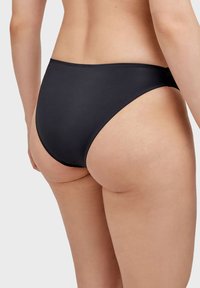 Fondo di bikini nero con un design a gamba alta, texture liscia e cuciture minime. La vista posteriore mostra una vestibilità senza cuciture.