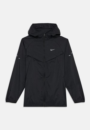 Melnā Nike kapucēta vējjakas, ar pilnu priekšējo rāvējslēdzēju, elastīgām aprocēm un atstarojošo logotipu uz krūtīm un rokām.