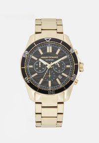 Orologio in acciaio inox dorato con lunetta nera, quadrante grigio testurizzato e indici delle ore dorati. Presenta sottodial e una finestra della data alle 4.