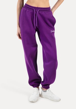 Pantalones de chándal de algodón morados con cintura elástica y cordón, que presentan tobillos ajustados y un detalle de logo bordado.