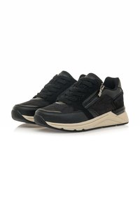 Zapatillas deportivas negras con una parte superior de ante y cuero, que cuentan con un acento de cremallera, patrones texturizados y una suela beige.