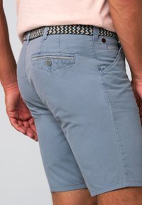 Light blue shorts with a textured fabric, featuring a side pocket, back pocket with button, and a patterned woven belt.