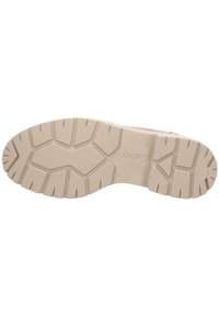 Sole of a beige shoe with a rugged design featuring deep grooves and a textured surface for traction. Includes branding details.