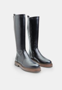 Stivali neri in pelle al ginocchio con finitura liscia, punta arrotondata e zip laterale. Presentano una suola piattaforma in brown testurizzata.