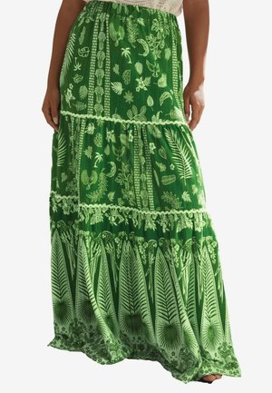 Flowy, tiered maxi skirt in vibrant green fabric, featuring white botanical prints and lace accents, with an elastic waistband for comfort.