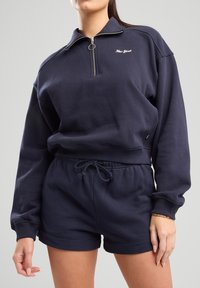 Navy blue sweatshirt with half-zip collar and embroidered "New York" logo, paired with matching navy shorts featuring an adjustable drawstring.
