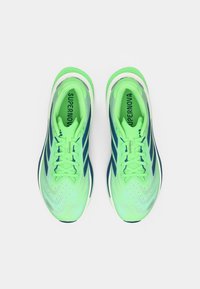 Αθλητικά παπούτσια σε φωτεινό πράσινο και ναυτικό μπλε, με υφασμάτινο διχτυωτό επάνω μέρος, κορδόνια και μαξιλαρωμένη σόλα με ζιγκ-ζαγκ μοτίβο.