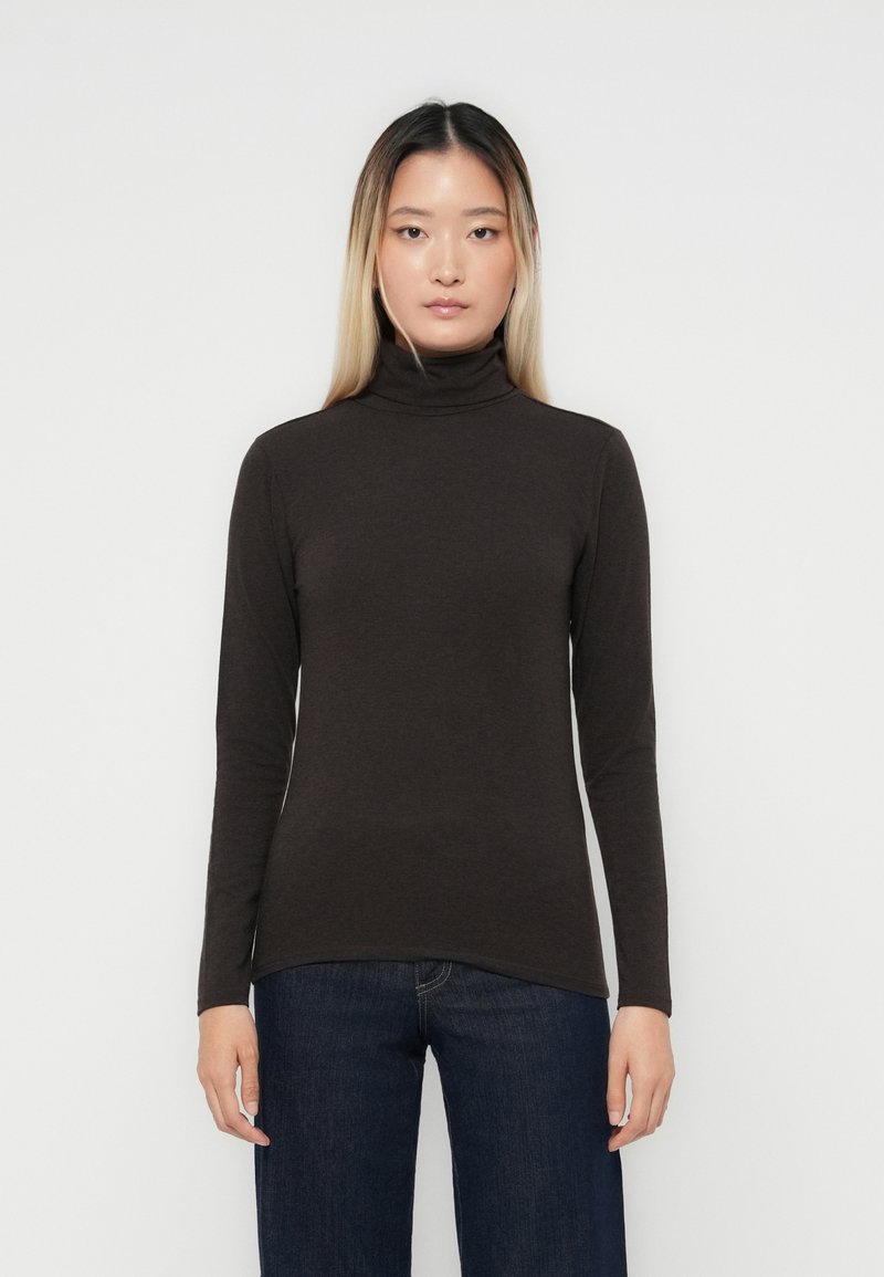 Mörkbrun polotröja i mjukt tyg, med lång ärm och en kroppsnära design, parat med mörkblå jeans.