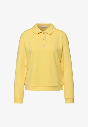 Polo amarillo de manga larga con tres botones decorativos y puños acanalados, mostrado sobre un fondo blanco.