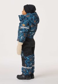 Värikäs talvipuku sinisen ja mustan sävyissä eläinkuvioilla, joka sisältää paksun takin, säädettävän hupun ja lapaset, yhdistettynä tukevin saappaisiin.