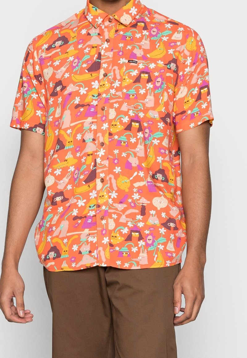Chemise à manches courtes boutonnée avec un fond orange vif et un motif coloré abstrait de visages de dessins animés, fleurs et formes.