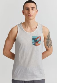Maiou gri deschis din bumbac, cu un buzunar colorat cu un imprimeu tropical. Textură netedă, decolteu rotunjit și design fără mâneci.