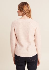 Helles pinkes Sweatshirt mit weicher Textur, verziert mit dezenten Pailletten und einem runden Ausschnitt. Schmale Passform mit gerippten Bündchen und Saum.