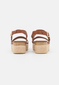 Ruske faux leather platform sandle sa tkanim jute đonom, podesivim remenom oko članka i detaljem od zlatne boje.