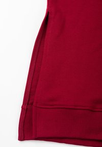 Rode trui stof met een gladde textuur. Voorzien van geribde zoom en zijsplitten voor bewegingsvrijheid. Strakke naden en moderne snit.