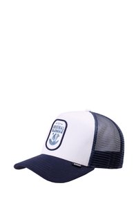 Cappello trucker bianco e blu navy con rete sul retro e patch frontale con la scritta "Original Djinns" che presenta un design di onde e piante.