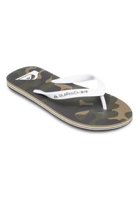 Tongs à motif camo avec une semelle texturée noire et olive, des brides en caoutchouc blanches et un logo blanc contrastant.