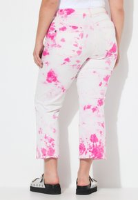 Vita denimjeans med rosa tie-dye-mönster, cropped längd, fransad fåll och två bakfickor. Bärs med svarta platåskor.