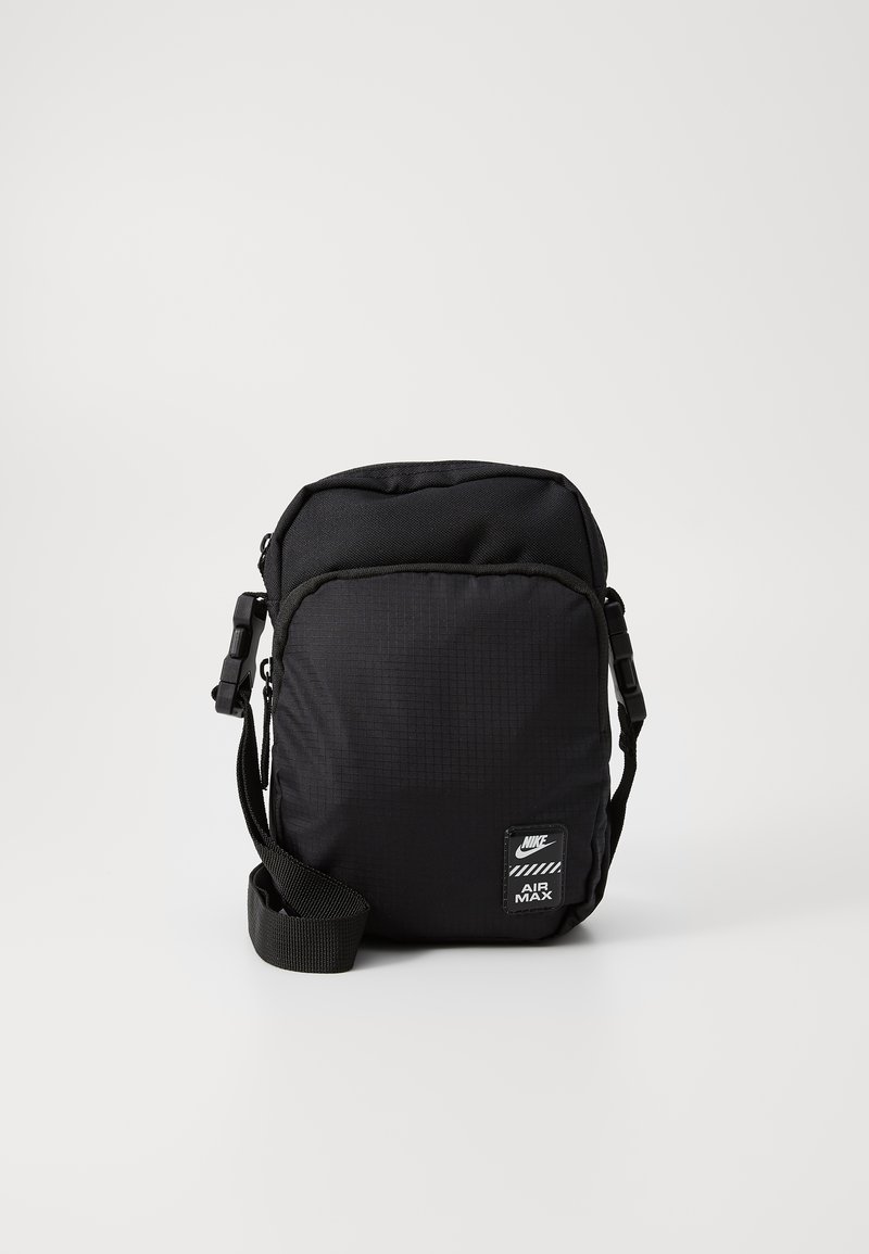 Bolso negro Nike Air Max, hecho de nylon texturizado, con correa ajustable y parche del logo. Forma rectangular compacta con cierre de cremallera.