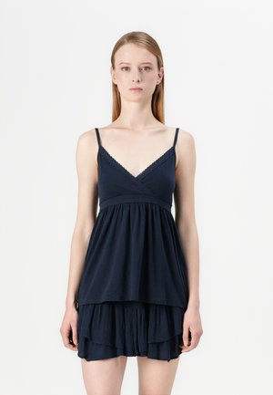 Navyblauw mouwloos jurkje met een V-hals, kantafwerking en een gelaagde, gerimpelde rok. Gemaakt van een zachte, lichte stof.