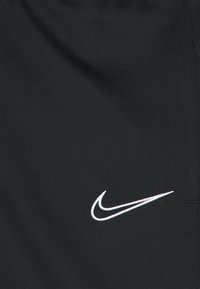 Zwarte sportshorts met een gladde textuur hebben een wit Nike swoosh-logo aan de linkerkant. Het materiaal lijkt licht en ademend te zijn.