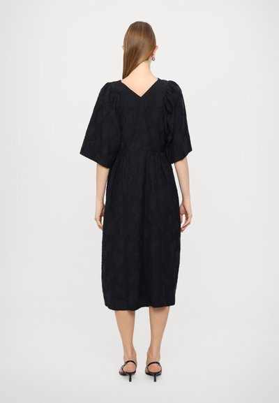 Zwart midi-jurk met puffmouwen, een V-back, textiel met een subtiele print en een geplooide taille. Draag met zwarte hakken sandalen.